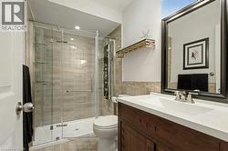 Bathroom with vanity, a stall shower, and tile walls - 