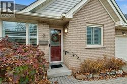 Doorway to property featuring roof with shingles, a garage, and brick siding - 