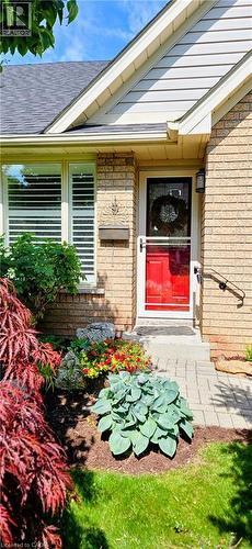 Brick facade featuring a vibrant red entry door with a white screen door and a black exterior light fixture - 165 Main Street E Unit# 9, Grimsby, ON - Outdoor