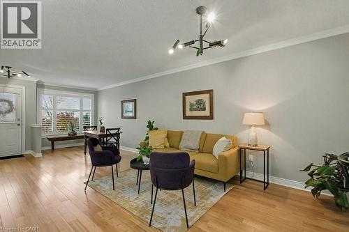 Living area featuring light wood-style floors, a chandelier, crown molding, and a textured ceiling - 165 Main Street E Unit# 9, Grimsby, ON - Indoor Photo Showing Living Room