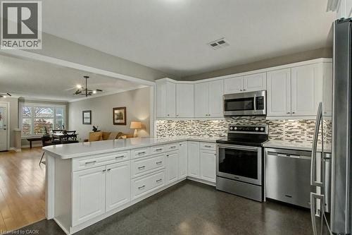Kitchen with appliances with stainless steel finishes, white cabinets, open floor plan, a peninsula, and tasteful backsplash - 165 Main Street E Unit# 9, Grimsby, ON - Indoor Photo Showing Kitchen With Upgraded Kitchen