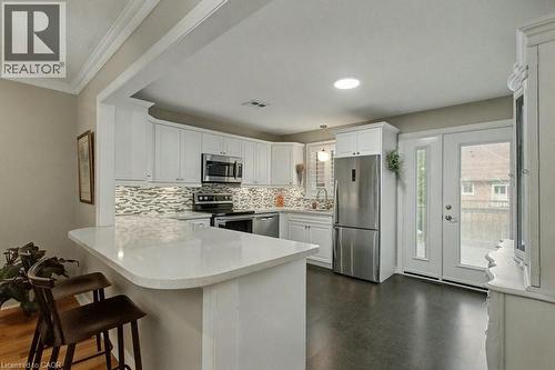 Kitchen featuring a peninsula, stainless steel appliances, white cabinetry, a kitchen breakfast bar, and tasteful backsplash - 165 Main Street E Unit# 9, Grimsby, ON - Indoor Photo Showing Kitchen With Upgraded Kitchen