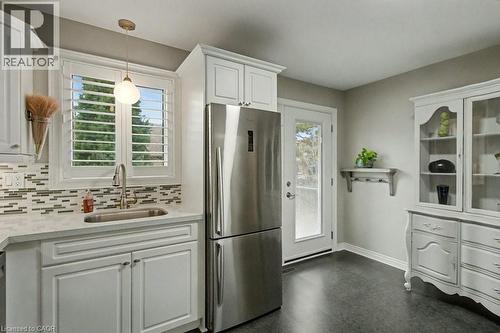 Kitchen with white cabinets, freestanding refrigerator, pendant lighting, tasteful backsplash, and light stone counters - 165 Main Street E Unit# 9, Grimsby, ON - Indoor Photo Showing Kitchen