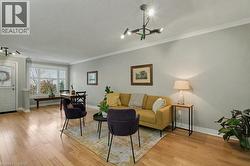 Living area featuring light wood-style floors, a chandelier, crown molding, and a textured ceiling - 