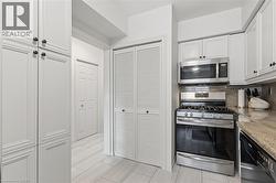 Kitchen featuring stainless steel appliances, white cabinetry, backsplash, and light stone counters - 