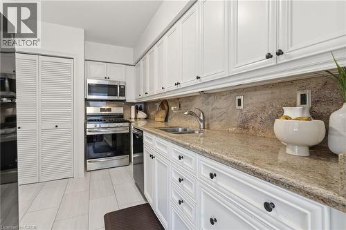Kitchen featuring appliances with stainless steel finishes, white cabinetry, light stone countertops, backsplash, and light tile patterned flooring - 2069 Meadowbrook Road Unit# 4, Burlington, ON - Indoor Photo Showing Kitchen With Double Sink