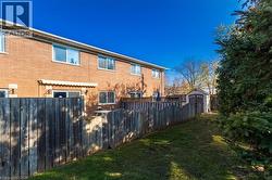 View of side of property with a fenced backyard, brick siding, and a storage shed - 