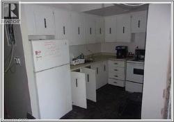 Kitchen with white appliances, white cabinetry, and light countertops - 