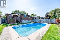 View of pool with a fenced backyard, a wooden deck, and a patio - 