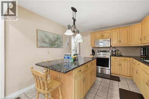 Kitchen with stainless steel electric stove, dark stone counters, light tile patterned floors, hanging light fixtures, and tasteful backsplash - 364 Roselawn Place, Waterloo, ON - Indoor Photo Showing Kitchen