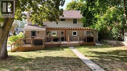 Back of house featuring a lawn, a deck, and roof with shingles - 