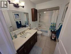 Bathroom featuring shower / bath combo with shower curtain, vanity, and light tile patterned floors - 