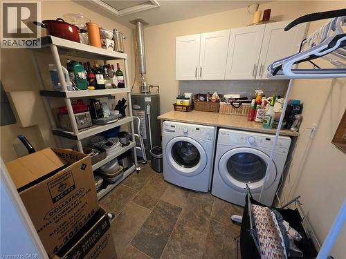 Washroom featuring stone finish flooring, water heater, separate washer and dryer, and cabinet space - 49 Bishop Reding Trail, Hamilton, ON - Indoor Photo Showing Laundry Room