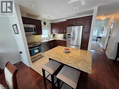 Kitchen with stainless steel appliances, backsplash, a kitchen island, dark brown cabinets, and recessed lighting - 49 Bishop Reding Trail, Hamilton, ON - Indoor Photo Showing Kitchen