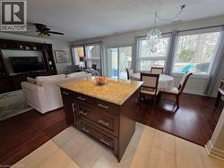 Kitchen with dark brown cabinets, a textured ceiling, light stone countertops, decorative light fixtures, and plenty of natural light - 