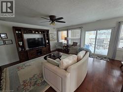 Living room with a textured ceiling, dark wood-type flooring, and ceiling fan - 