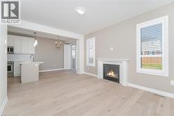 Unfurnished living room with a glass covered fireplace, light wood-style flooring, and plenty of natural light - 