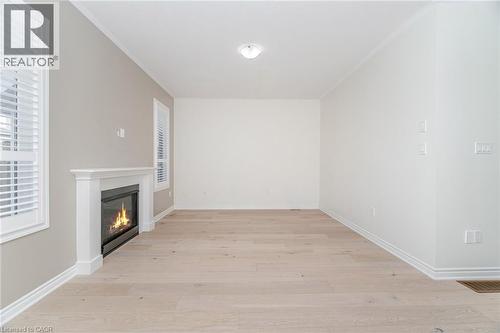 Unfurnished living room featuring a glass covered fireplace, light wood finished floors, and crown molding - 28 Pickett Place, Cambridge, ON - Indoor Photo Showing Other Room With Fireplace