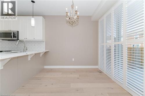 Kitchen featuring decorative backsplash, a breakfast bar area, light wood finished floors, a chandelier, and stainless steel microwave - 28 Pickett Place, Cambridge, ON - Indoor Photo Showing Kitchen