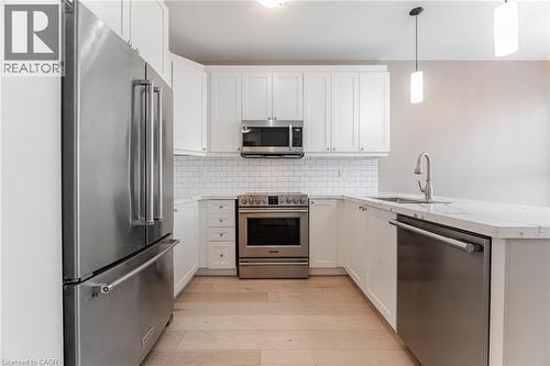 Kitchen featuring appliances with stainless steel finishes, light wood-style floors, white cabinetry, light stone countertops, and pendant lighting - 28 Pickett Place, Cambridge, ON - Indoor Photo Showing Kitchen With Stainless Steel Kitchen With Upgraded Kitchen