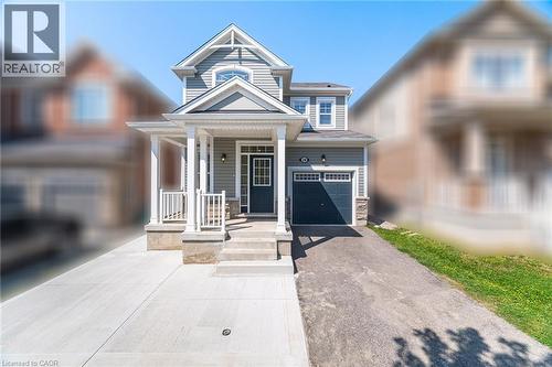View of front of house with covered porch, driveway, a garage, and stone siding - 28 Pickett Place, Cambridge, ON - Outdoor With Facade