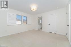 Unfurnished bedroom featuring light carpet, ensuite bath, and a closet - 