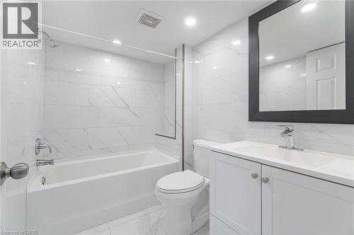 Full bathroom featuring tile walls, light marble finish flooring, washtub / shower combination, vanity, and recessed lighting - 28 Pickett Place, Cambridge, ON - Indoor Photo Showing Bathroom