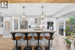 Kitchen featuring white cabinetry, recessed lighting, hanging light fixtures, stainless steel appliances, and a breakfast bar - 