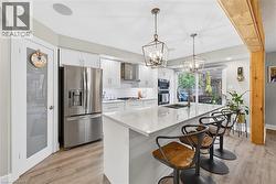 Kitchen featuring appliances with stainless steel finishes, white cabinets, pendant lighting, light stone countertops, and a kitchen breakfast bar - 