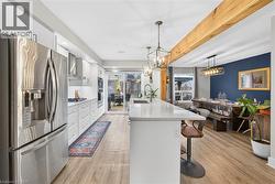 Kitchen with appliances with stainless steel finishes, white cabinetry, light stone counters, a breakfast bar, and pendant lighting - 