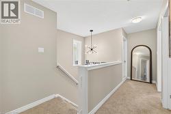 Hall featuring an upstairs landing, light colored carpet, and a chandelier - 