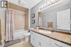 Bathroom with vanity, shower / bath combination with curtain, and light tile patterned floors - 