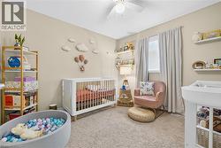 Carpeted bedroom with a crib and ceiling fan - 
