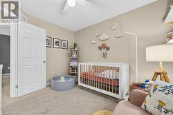 Carpeted bedroom with a crib and ceiling fan - 