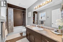 Bathroom with shower / bath combo, vanity, and light tile patterned floors - 