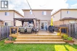 Rear view of house featuring a gazebo, a fenced backyard, a deck, and outdoor dining area - 