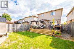Rear view of house with a fenced backyard, a gazebo, a wooden deck, and brick siding - 