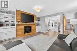 Living room with light wood-style flooring, a large fireplace, built in shelves, and a chandelier - 