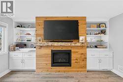 Living room featuring light wood-type flooring, a fireplace, and built in features - 