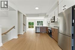 Kitchen featuring appliances with stainless steel finishes, light countertops, white cabinetry, and light wood-type flooring - 