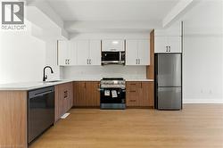 Kitchen featuring stainless steel appliances, brown cabinets, light wood-type flooring, white cabinets, and a peninsula - 
