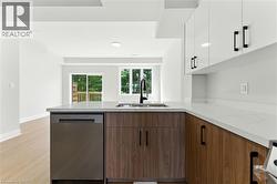 Kitchen featuring dishwasher, a peninsula, modern cabinets, white cabinetry, and light stone counters - 