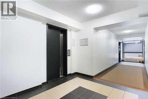 Hall with elevator, a textured ceiling, and tile patterned floors - 17 King Street E Unit# 205, Dundas, ON 