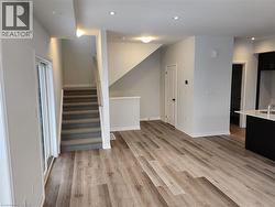 Unfurnished living room featuring light wood finished floors, stairs, and recessed lighting - 