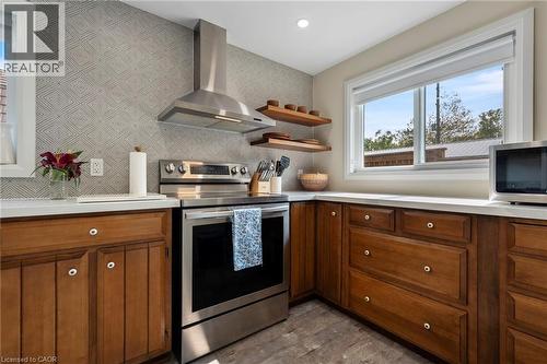 Kitchen with brown cabinetry, stainless steel appliances, wall chimney exhaust hood, light countertops, and dark wood-type flooring - 197 Cedar Drive, Turkey Point, ON - Indoor Photo Showing Kitchen
