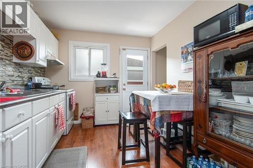 Kitchen featuring white electric range, backsplash, white cabinets, and wood finished floors - 129 River Road E, Kitchener, ON - Indoor Photo Showing Other Room