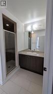 Full bath featuring vanity, a stall shower, and light tile patterned flooring - 
