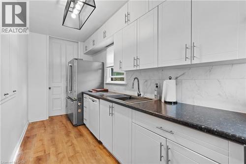 Kitchen featuring white dishwasher, white cabinets, light wood-style flooring, decorative backsplash, and freestanding refrigerator - 5368 Menzie Street, Niagara Falls, ON - Indoor Photo Showing Kitchen With Upgraded Kitchen