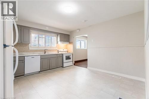 Kitchen featuring white appliances, gray cabinets, a sink, light countertops, and baseboards - 2340 King Street E, Hamilton, ON - Indoor Photo Showing Kitchen