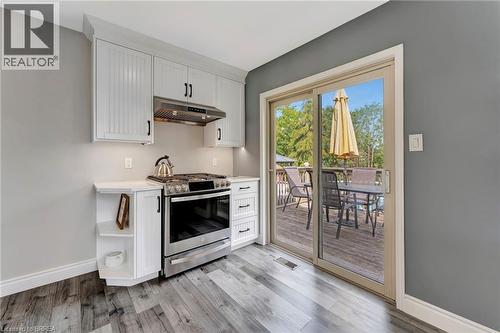 Kitchen featuring stainless steel range with gas stovetop, under cabinet range hood, light wood finished floors, and white cabinets - 1565 Old Brock Street, Vittoria, ON - Indoor Photo Showing Kitchen